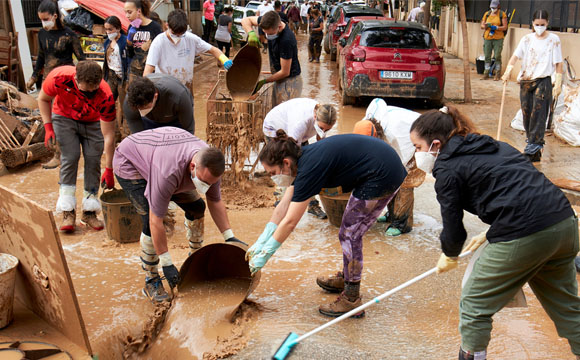 gente con mascarilla sacando barro de la calle